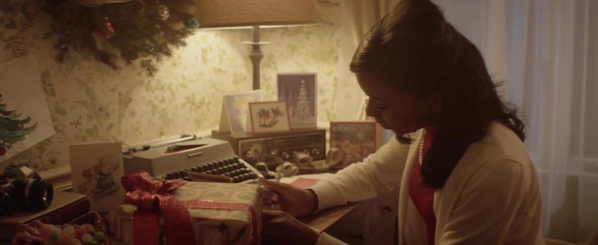 A girl sets a present down on a desk and writes in a card