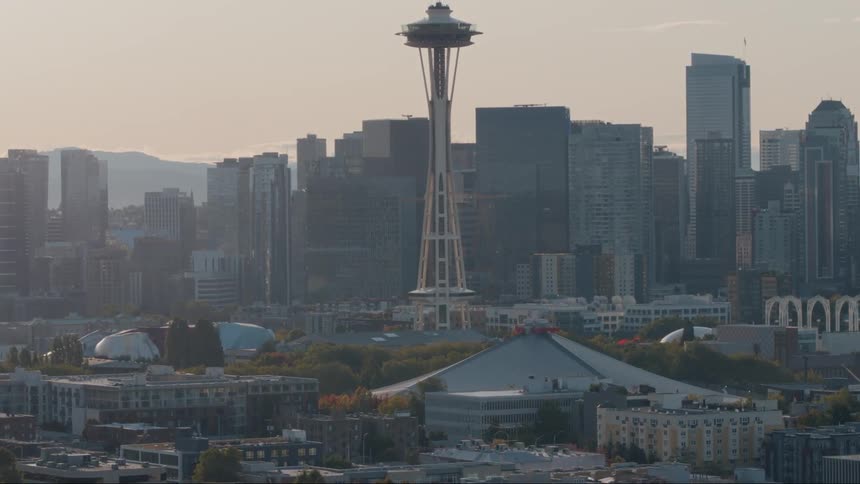The space needle appears from behind trees until you can see the whole of seattles skyline
