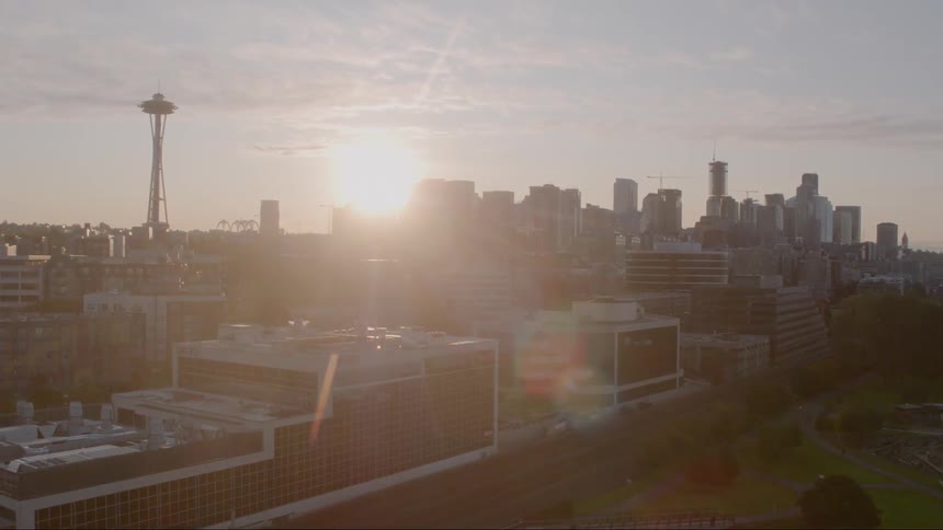 A city close to the shore with the sun and the sky in the background