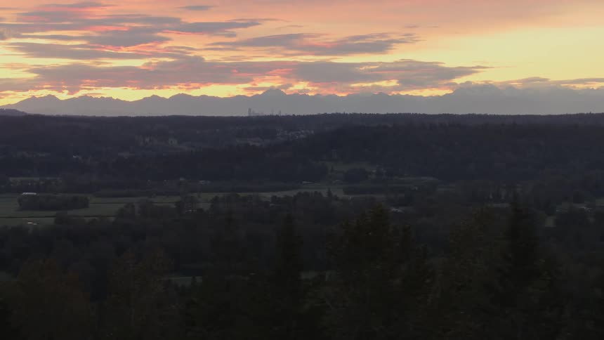 A flat valley is dimly lit as the sun sets