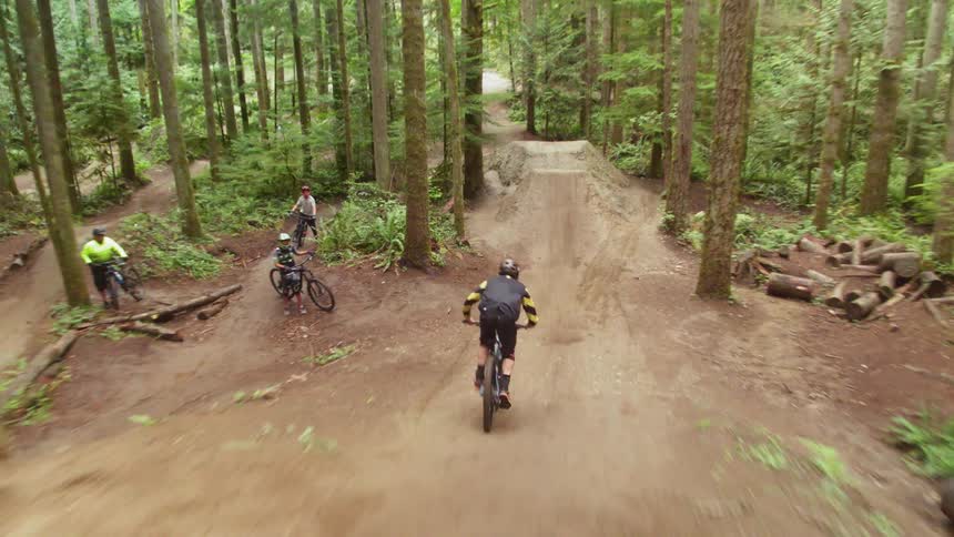 Mountain biker jumps over on forest track in the forest during daylight