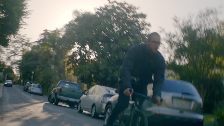 A person is riding his bike down the street at sunset