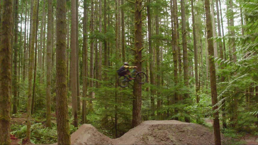 A man doing bike trick at forest