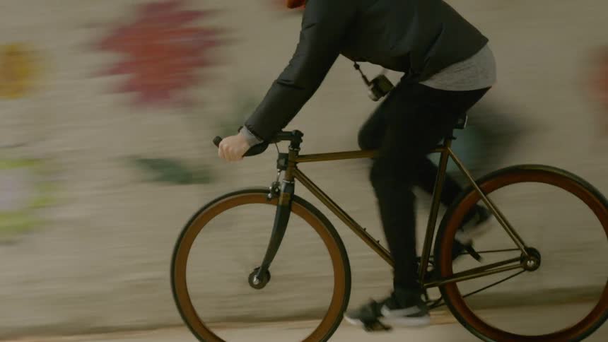 A bald man riding his bike quickly down the road