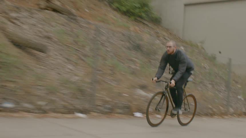 A man with a camera around his neck riding a bike