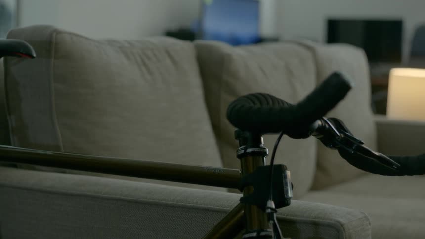 A person quickly grabbing and carrying away a bicycle that was leaning against a sofa