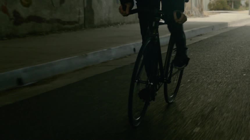 A person is riding a bicycle down a street under a tunnel