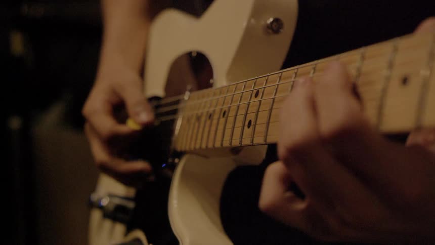 Close up view of an electric guitar while musician is playing on it