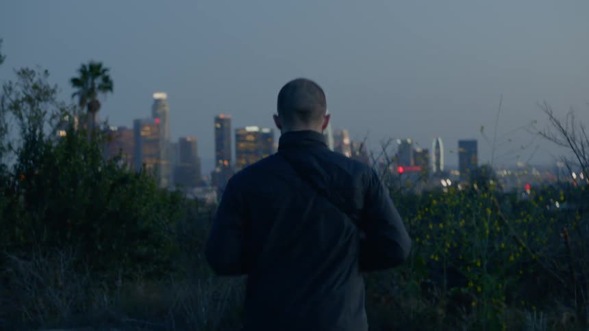 Man on a bicycle takes a photo of the city skyline at sunset with his camera