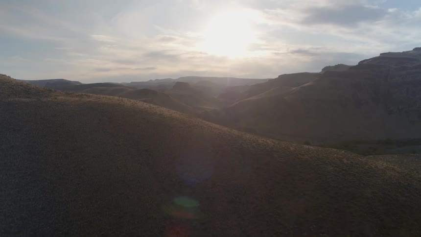 A hilly landscape is illuminated by the evening sun