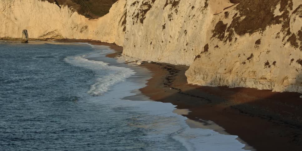 A scenery of ocean waves hitting the land
