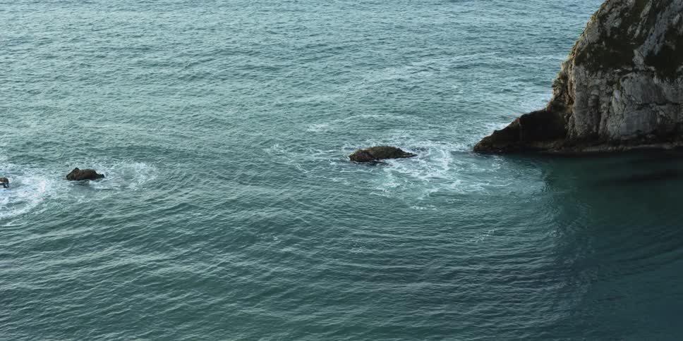Waves swirl around islets and rocks where ocean meets cliff