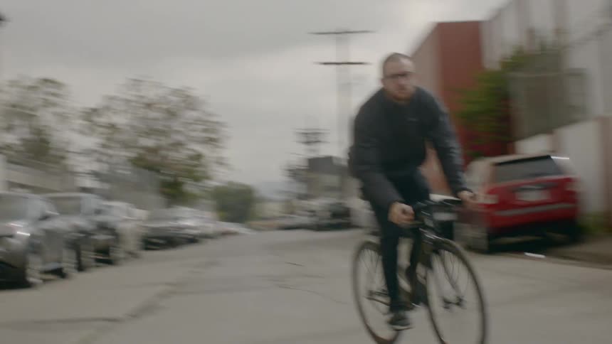 A man rides his bike through an industrial area of a city