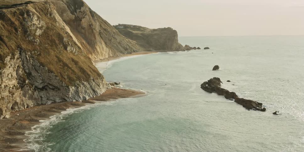 An ocean coast with steep hill sides and a rock outcropping