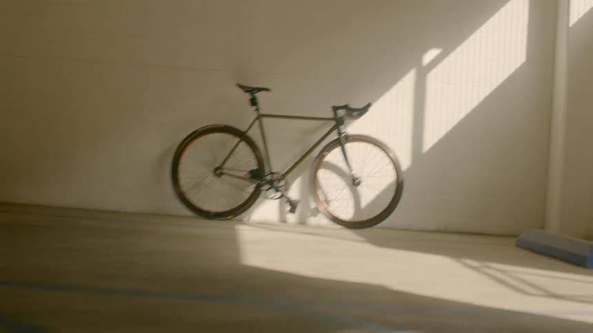 A 10 speed bike is leaning against the wall next to an empty parking space in a parking garage