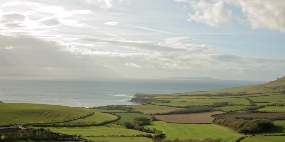 A static shot of farmland by an ocean