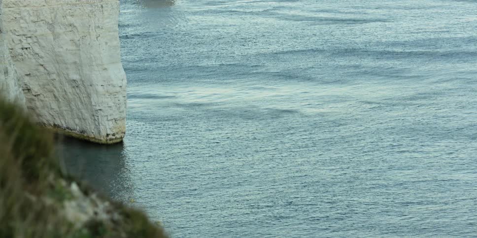 Water in an ocean swells around a rocky cliff