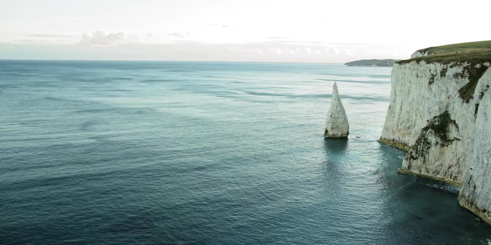 Calm waters roll against white chalk cliffs at daytime