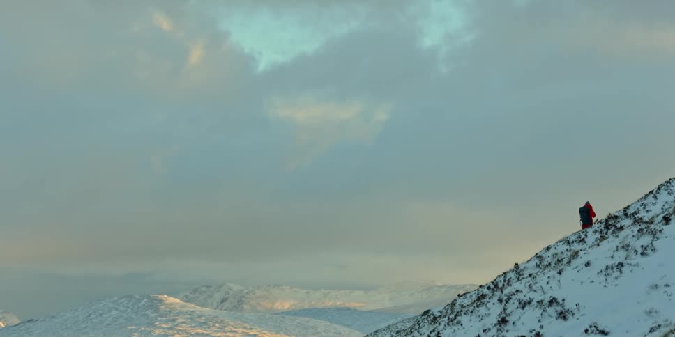A person is climbing a mountain on a cloudy day