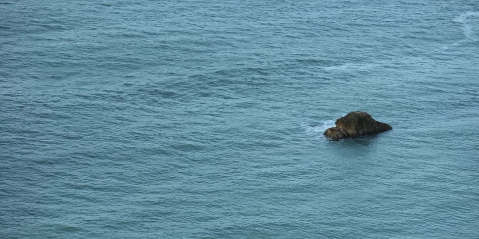 A single stone is rising above the ocean