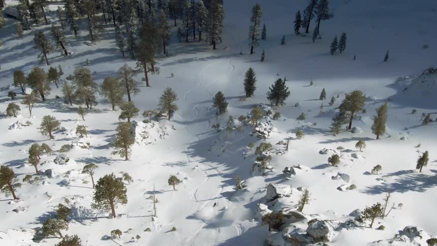 A man skis down a slope of a snowy mountain on a beautiful clear and sunny day