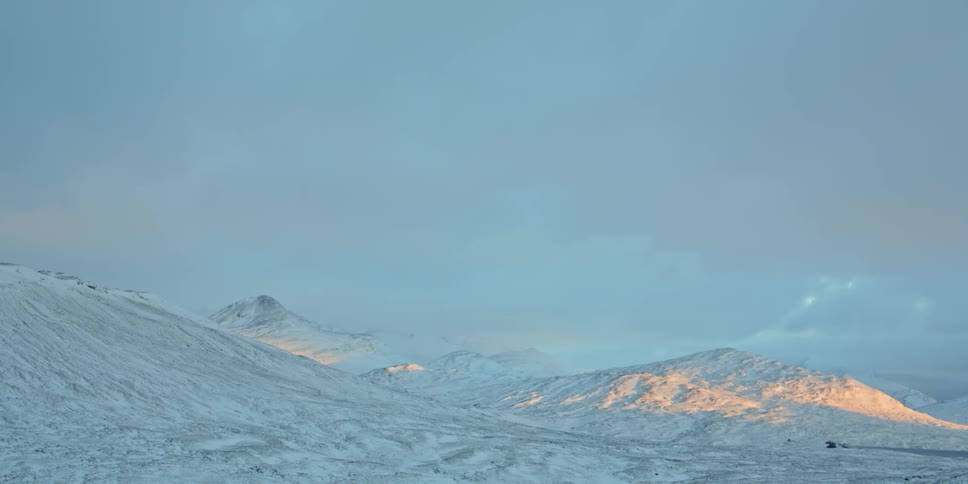 Snow covered mountains are visible under a cloudy sky