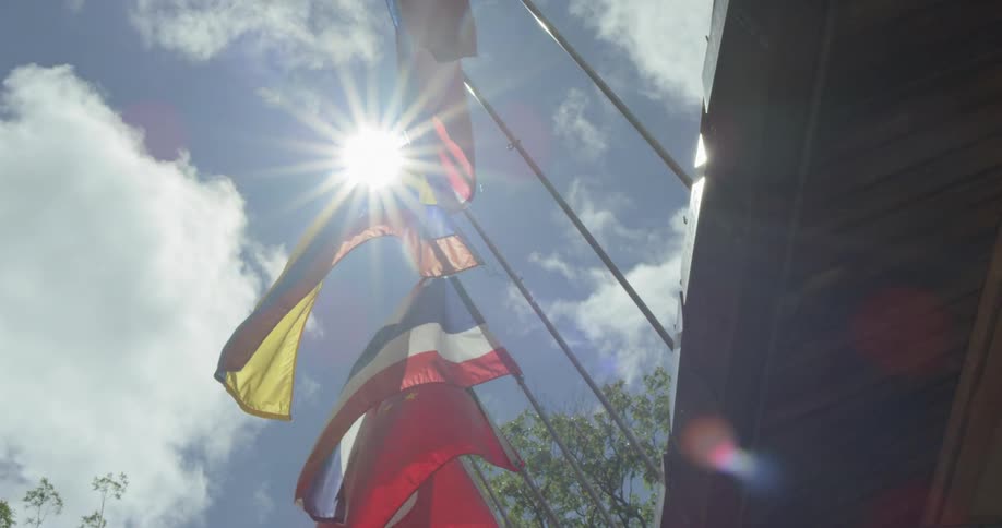 Flags of different international countries backlit under sun light