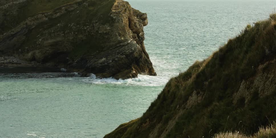 Low ocean waves washing between two headlands