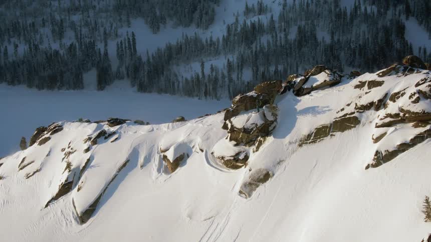 Rocks are visible through the snow on a mountain ridge