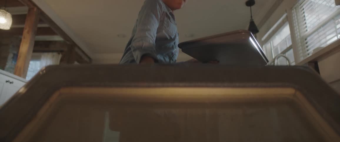 A little girl puts a tray of cookies in the oven