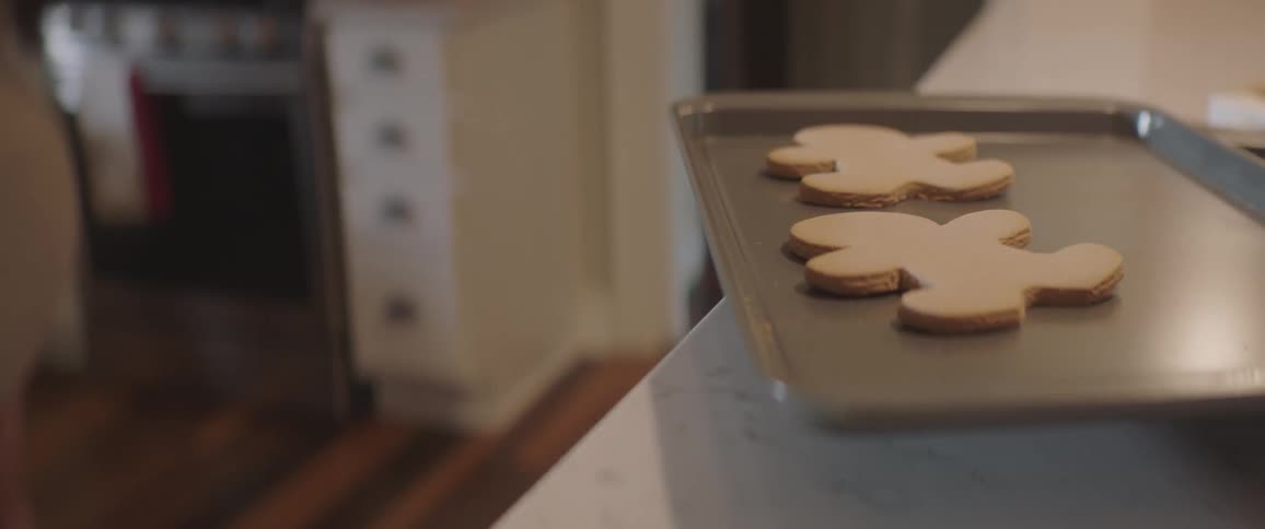 A pair of gingerbread men cookies cooling on cookie sheet on kitchen counter