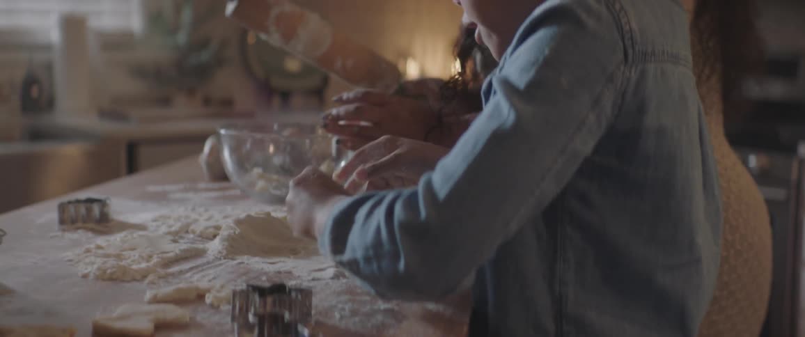 Mother and daughter roll out cookies on kitchen island