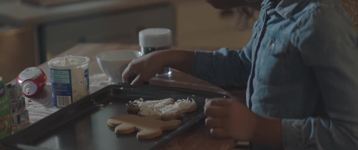 A young girl decorates cookies with her mom