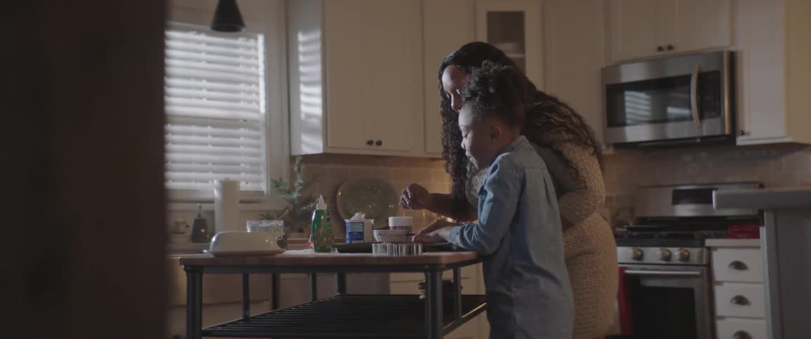 A woman helping a girl to make cookies in a kitchen