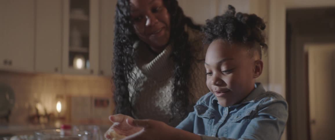 A woman and a girl in a kitchen using cookie cutters to shape cookie dough
