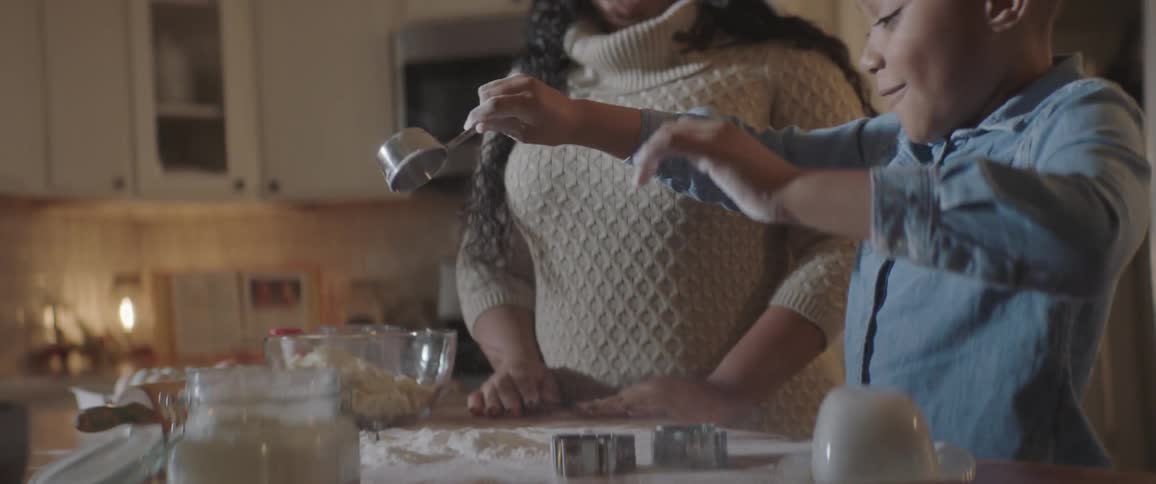 Daughter cooking a cake with the help of her mother