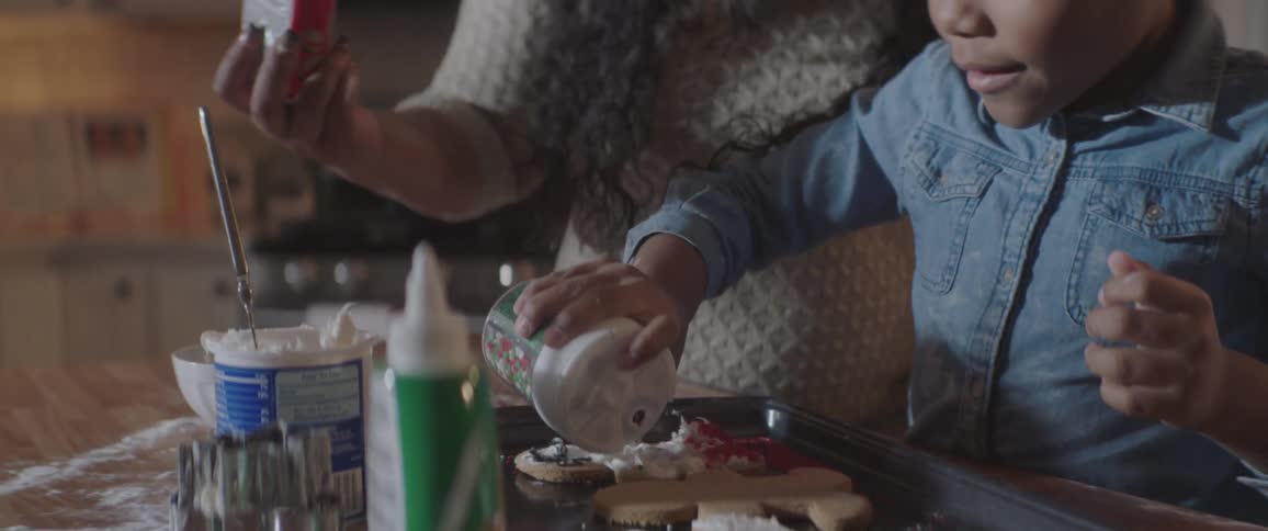 Black woman helps black child make cookies in the kitchen