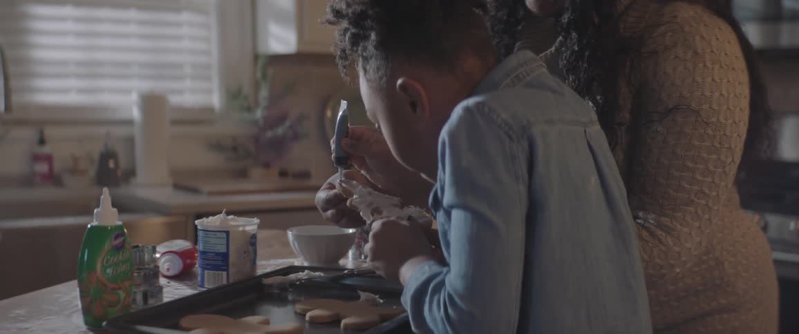 Mother and daughter decorating gingerbread cookies in the kitchen