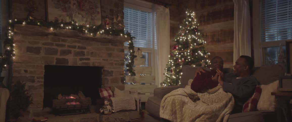 Two people hold hands sitting on the couch