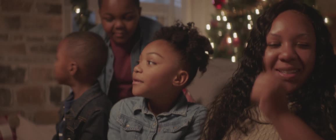 Family sits on a sofa near a christmas tree