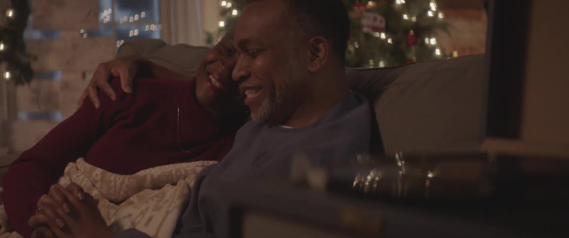 Black man and woman sit on the couch andtalk at home at night