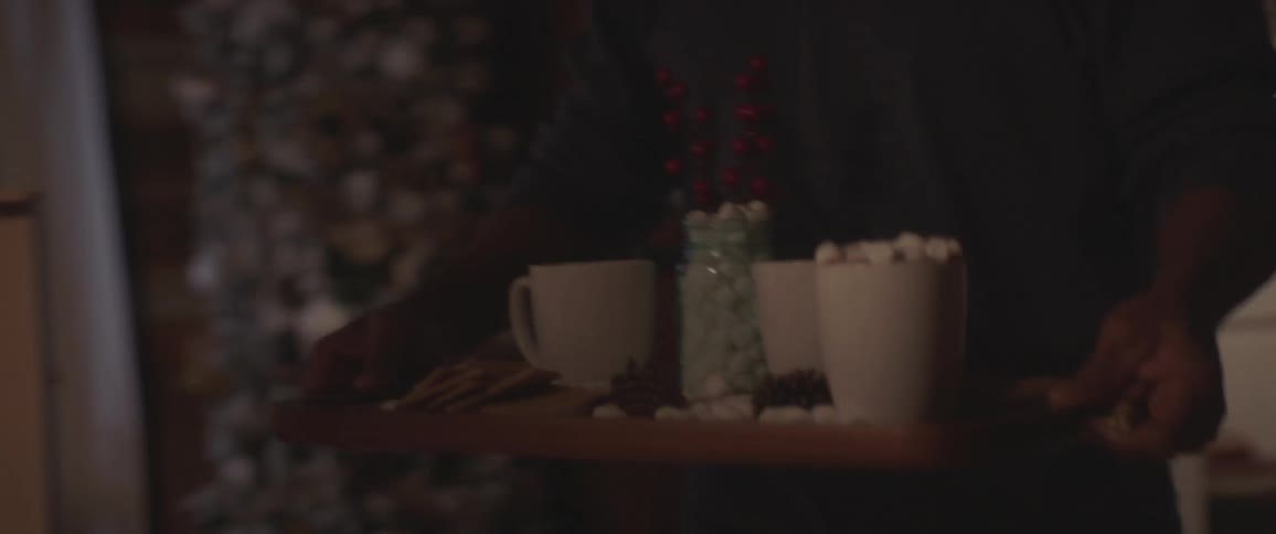 A man carries a tray with drinks in to his family