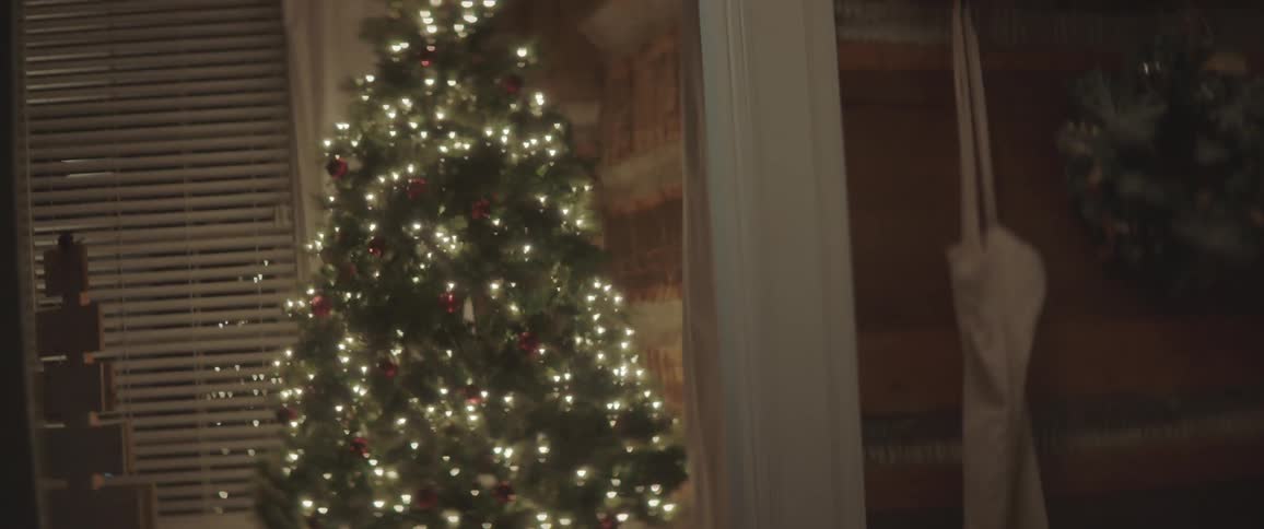 Lights glow in an indoor christmas tree with red ornaments