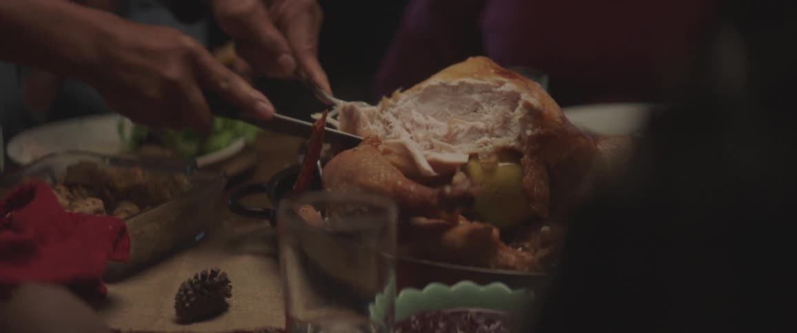 A man cuts meat for a young girl then slices another portion and places it on their plate