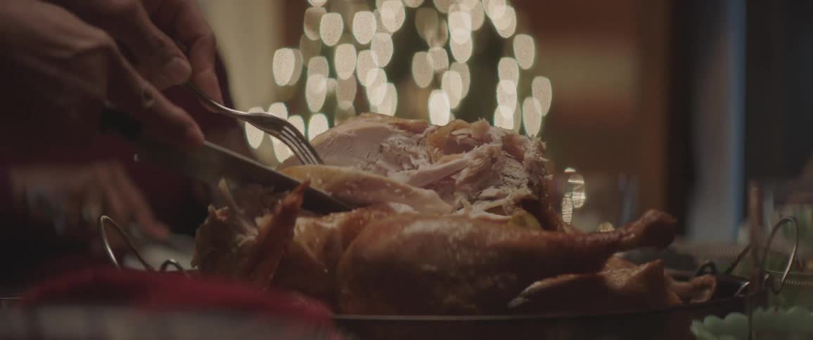 A woman carves a turkey and serves it