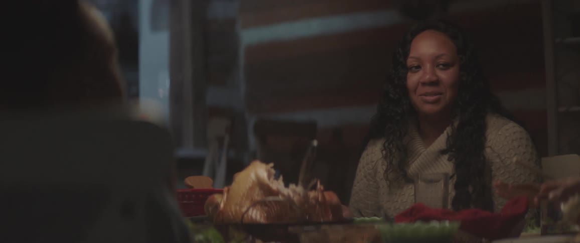 A woman smiles and laughs while talking at the dinner table with her family