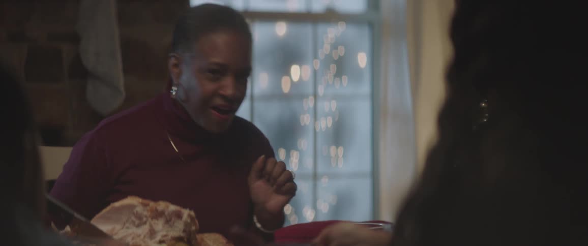 Black family sitting at the table has a christmas dinner and talks to each other at home