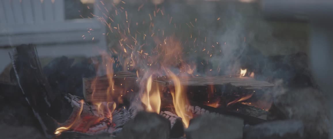 Wood burning in a fire pit with a white lawn chair in the background