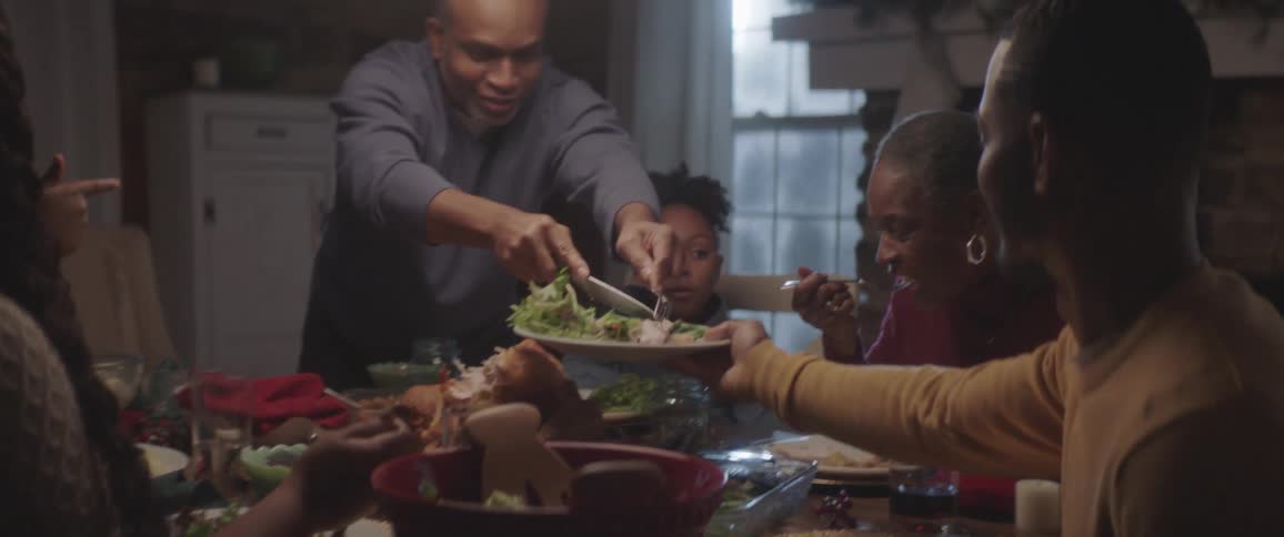 A man serves turkey to a family member at a family dinner