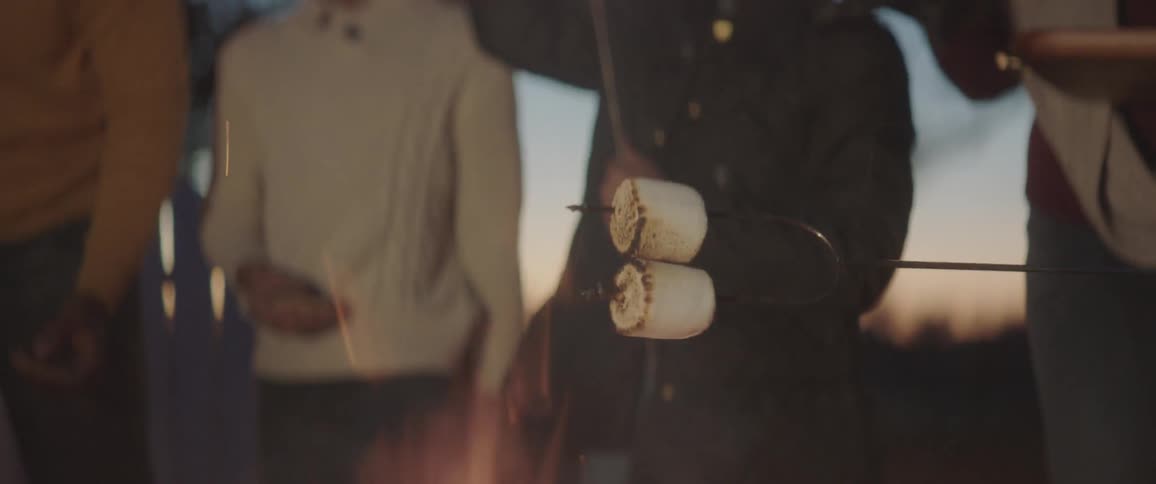 People putting marshmallows on sticks and roasting them over flames